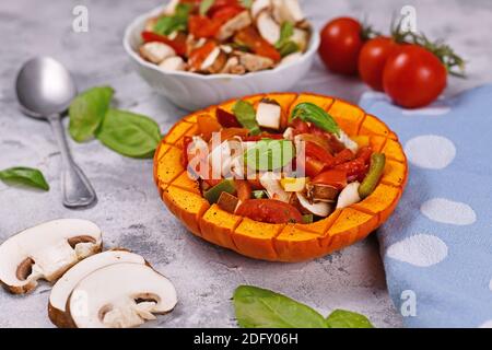 Gebackenes veganes rotes Kürbisgemüse mit Paprika, Tomaten und Pilzen, umgeben von Zutaten Stockfoto