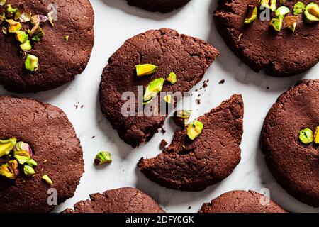 Hausgemachte vegane Schokoladenkekse mit Pistazien auf weißem Marmorboden. Veganes Backkonzept. Stockfoto