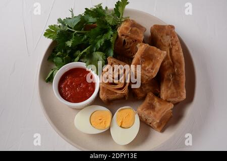Jachnun oder Jahnun, jemenitisches jüdisches Gebäck, serviert mit frisch geriebenen Tomaten und gekochtem Ei und Zhug, aus den Adeni-Juden, und traditionell Stockfoto