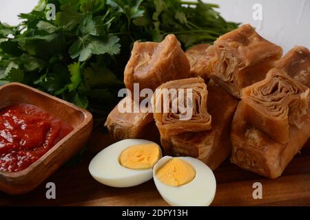 Jachnun oder Jahnun, jemenitisches jüdisches Gebäck, serviert mit frisch geriebenen Tomaten und gekochtem Ei und Zhug, aus den Adeni-Juden, und traditionell Stockfoto