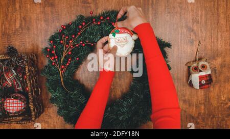 Frau Dekoration Weihnachtskiefer Kranz mit roten Winterbeeren, Ornamente und Tannenzapfen, Nahaufnahme von oben auf Holzhintergrund Stockfoto