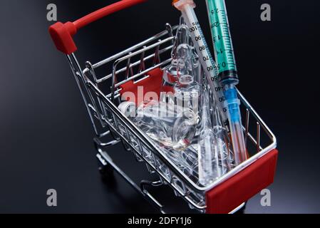 Spritzen und Ampullen mit Medizin im Warenkorb. Kauf von Medikamenten Cocept Stockfoto