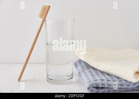 Bambuszahnbürste aus Glas und Badetücher auf einem weißen Hintergrund Stockfoto