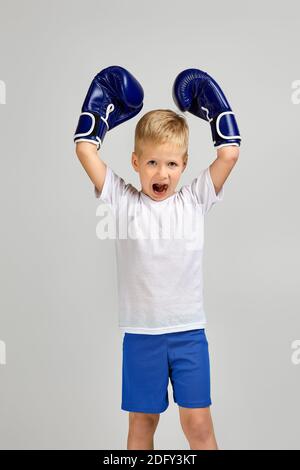 Happy Little Boxkampf Junge in blauen Boxer Handschuhe ist Gestikulierenden Sieg Stockfoto