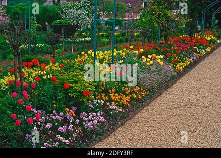 DER GARTEN UND DAS HAUS VON CLAUDE MONET IN GIVERNY, NORMANDIE, FRANKREICH. MAI. 2010 der zentrale Weg zum Haus mit bunten Blumen und Rosen Stockfoto