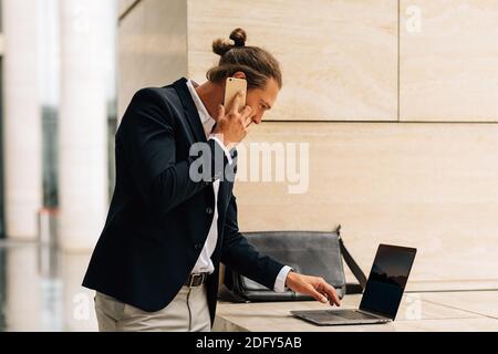 Seitenansicht des Geschäftsmannes, der auf einem Handy spricht und Eingabe Stockfoto