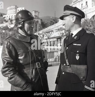 50er Jahre, historisch, Monte Carlo und zwei Polizisten der Polizei von Monaco sprechen zusammen in diesem Bild von J. Allan Cash. Einer trägt eine dicke Lederjacke und Helm ist ein Motorradpolizist und der andere in einer traditionelleren Uniform mit Mütze, ist ein Offizier der bewaffneten Nationalpolizei. Mit einer großen Polizei im Vergleich zur Bevölkerung ist das winzige mediterrane Fürstentum Monaco einer der sichersten - aber teuersten - Orte der Welt zum Leben. Stockfoto