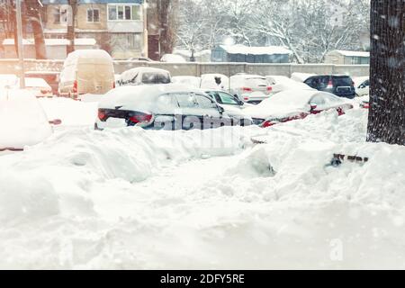 Apartment oder Bürogebäude Parkplatz mit vielen Autos von Schnee bedeckt stank nach schweren Schneesturm Schneefall am Wintertag. Schneeverwehungen und eingefroren Stockfoto