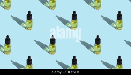 Glasflasche mit Öl, mit Pipette. Kosmetisches Öl, Hautpflege für Gesicht und Körper. Nahtloses Muster, Schatten, blauer Hintergrund. Stockfoto