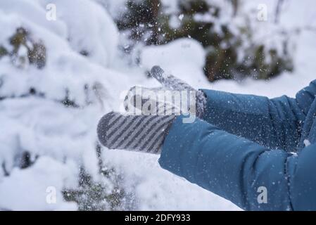 Frau in Fäustlingen klatscht Hände in den Schnee. Stockfoto