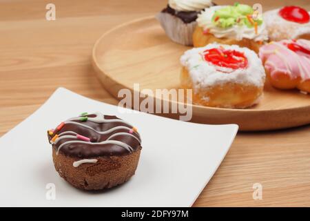 Schmackhafter Donut in weißer Schale auf braunem Holztisch Hintergrund, Bäckerei Stockfoto