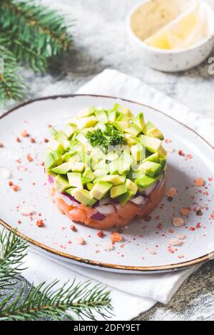 Salat aus rohem Lachs, Avocado und violetten Zwiebeln. Lachs-Tatar. Vorspeise für Silvester oder Weihnachtstisch Stockfoto