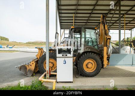 Gelber Traktor an der Tankstelle. Auffüllen. Schwere Ausrüstung. Stockfoto