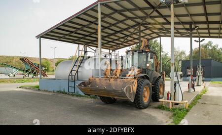 Gelber Traktor an der Tankstelle. Auffüllen. Schwere Ausrüstung. Tanks mit Kraftstoff. Stockfoto