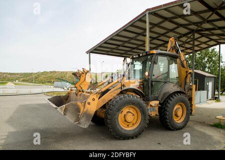 Gelber Traktor an der Tankstelle. Auffüllen. Schwere Ausrüstung. Tanks mit Kraftstoff. Stockfoto