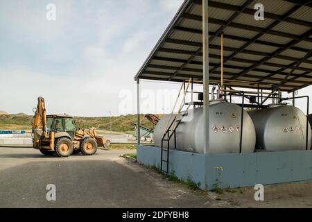 Gelber Traktor an der Tankstelle. Schwere Ausrüstung. Tanks mit Kraftstoff. Stockfoto