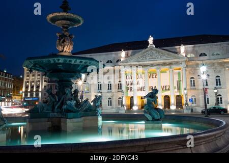 Spiegelung des Zeichens des Nationaltheaters am beleuchteten Brunnen am Rossio-Platz in Lissabon, Portugal. Nachts aufgenommen Stockfoto