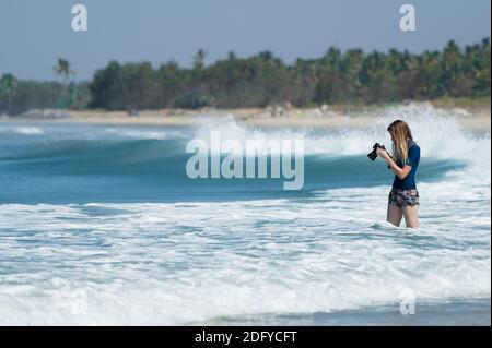 VARKALA, INDIEN - Mär 14, 2020: Eine Fotografin, die ihren Kamerabildschirm betrachtet und die Bilder am Strand betrachtet Stockfoto