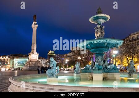 Beleuchteter Brunnen mit Säule von Pedro IV am Rossio Platz in Lissabon, Portugal. Aufgenommen während der Nacht Stockfoto