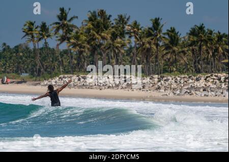 VARKALA, INDIEN - Mar 14, 2020: Ein indischer Mann Surfen im Stil mit seinen Händen offen und begrüßen die Küste Stockfoto