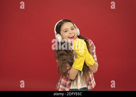 Machen Sie den Haushalt freudiger. Harmlose Reiniger mit einfachen Zutaten. Reinigungsparty. Mädchen tragen zur Reinigung Kopfhörer und Schutzhandschuhe. Musik hören und reinigen. Viel Spaß. Stockfoto