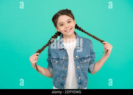 Happy girl Kind mit Beauty-Look halten lange Haare Zöpfe in Casual Fashion Style blauen Hintergrund, Frisur. Stockfoto