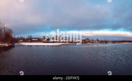 Panorama-Winterblick mit alten Häusern in der Nähe eines schneebedeckten Sees. Authentische nördliche Stadt Kem im Winter. Russland. Stockfoto