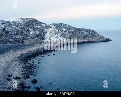 Erstaunlicher schwarzer Kiesstrand von Barents Meeresküste in der Nähe von Teriberka. Winter auf Kola Halbinsel, Murmansk Oblast, Russland. Stockfoto