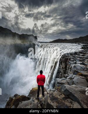 Wanderer, der in der Nähe des Dettifoss Wasserfalls in Island steht Stockfoto