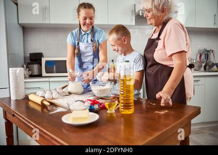 Bruder und Schwester kochen mit ihrer Oma in der Küche Stockfoto