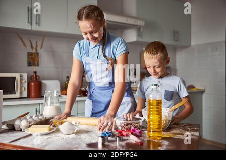 Zwei fröhliche Geschwister, die in der Küche mit Teig experimentieren Stockfoto