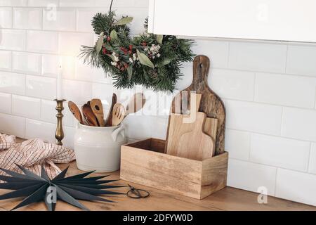 Nahaufnahme des Kücheninnenraums. Weihnachtsdekoration. Advent Blumenreifen Kranz. Schwarzer Stern aus Papier. Weiße Backsteinmauer, Metro-Fliesen, Holzarbeitsplatten mit Stockfoto