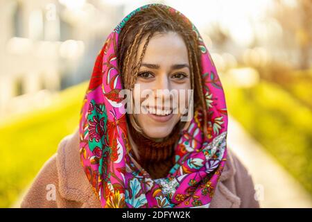 Porträt einer lächelnden jungen Frau mit Kopftuch in der Stadt Stockfoto