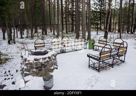 Ein ausgestatteter Ort zum Entspannen in einem Pinienwald, mit einem Steinofen und geschmiedeten Bänken. Stockfoto