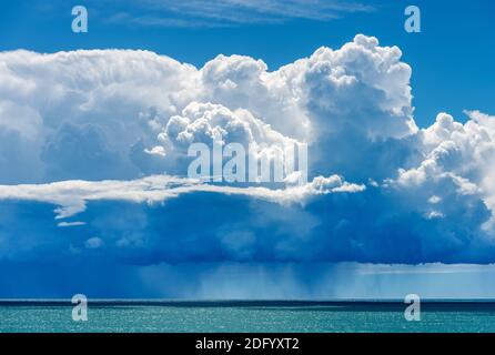 Schöne Cumulus Wolken (Cumulonimbus) auf blauem Himmel mit sintflutartigen Regen über dem Mittelmeer. Golf von La Spezia, Ligurien, Italien, Europa. Stockfoto