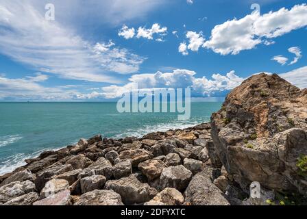 Felsbrocken Wellenbrecher und Mittelmeer am schönen Himmel mit Cumulus Wolken, Tellaro Dorf, Ligurien, Italien, Europa Stockfoto