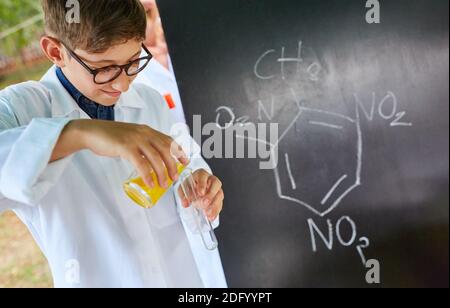 Kind vor einem Kreidetafel in der Lehrchemie Klasse während eines Experiments Stockfoto