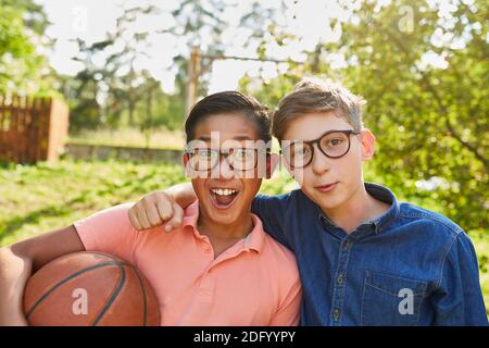 Fröhliche multikulturelle Kinder als Freunde mit Basketball im Sommercamp Im Park Stockfoto