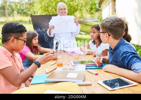 Gruppe von Kindern und Lehrer in der Nachhilfe Chemie Klasse in Sommerschule Stockfoto