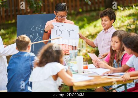 Die Gruppe der Kinder mit der Molekülzeichnung im Sommer tutoring Chemiekurs Stockfoto