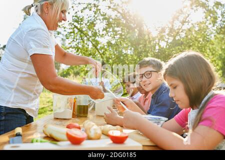 Kinder lernen zusammen mit einem Lehrer gesund zu kochen Der Kochkurs im Sommercamp Stockfoto