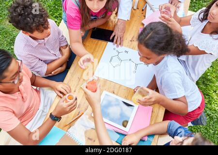 Gruppe multikultureller Kinder, die im Sommer ein Experiment machen Studienkurs Chemie Stockfoto