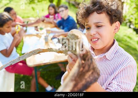 Kinder im ökologischen Sommerlager schauen neugierig auf den Baum Rinde unter der Lupe Stockfoto