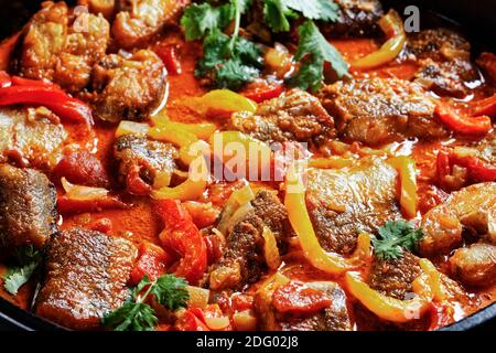 Moqueca baiana - brasilianischer Fischeintopf mit weißem Fisch mit Paprika, Limettensaft, gehackten Tomaten, Kokosmilch, serviert auf einem schwarzen Gericht mit Koriander Stockfoto