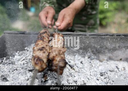 Person Kochen shish Kebabs auf Spieße im Hinterhof Stockfoto