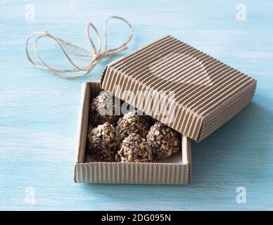 Bonbons mit Erdnussbutter, Schokoladenglasur und Waffelbröseln in einer festlichen Bastelkiste auf blauem Hintergrund, selektiver Fokus. Köstliches hausgemachtes Dessert Stockfoto