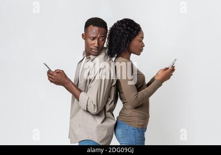 Afrikanischer Mann und Frau stehen zurück an den Rücken, mit Smartphones Stockfoto