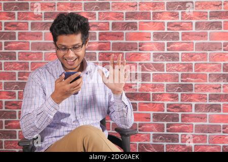 Glücklicher junger Mann in einer Videokonferenz über Smart diskutieren Telefon Stockfoto