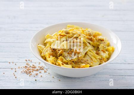 Eingelegter chinakohl mit Knoblauch und Gewürzen, Senf, Kurkuma, Paprika in einer weißen Schüssel auf blauem Hintergrund, selektiver Fokus. Gesundes orientalisches Stockfoto