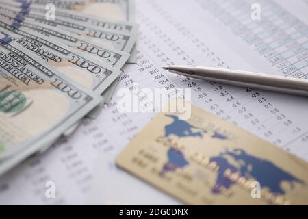 Bankkreditkarte und Dollar liegen auf dem Tisch mit Zahlen Nahaufnahme Stockfoto